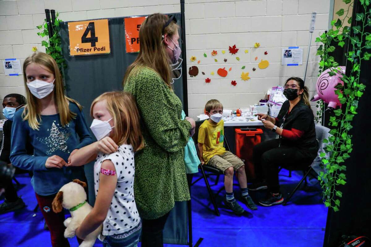 Henry Galush, 8 (seated center), prepares to receive the COVID-19 vaccine as his sisters and mom Alexandra Schmitt look on at Emmanuel Baptist Church in San Jose.