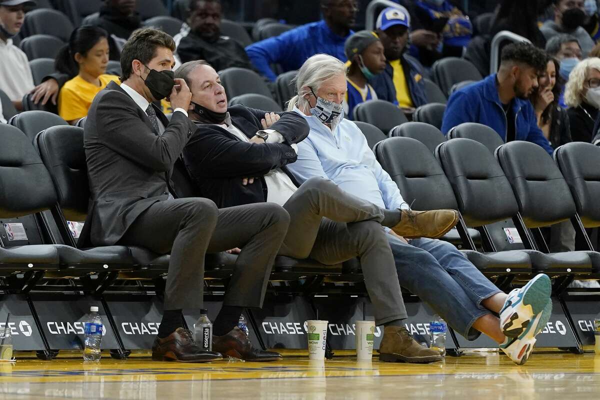Golden State Warriors general manager Bob Myers, left, sits next to owner Joe Lacob, middle, during a preseason NBA basketball game between the Warriors and the Denver Nuggets in San Francisco, Wednesday, Oct. 6, 2021.