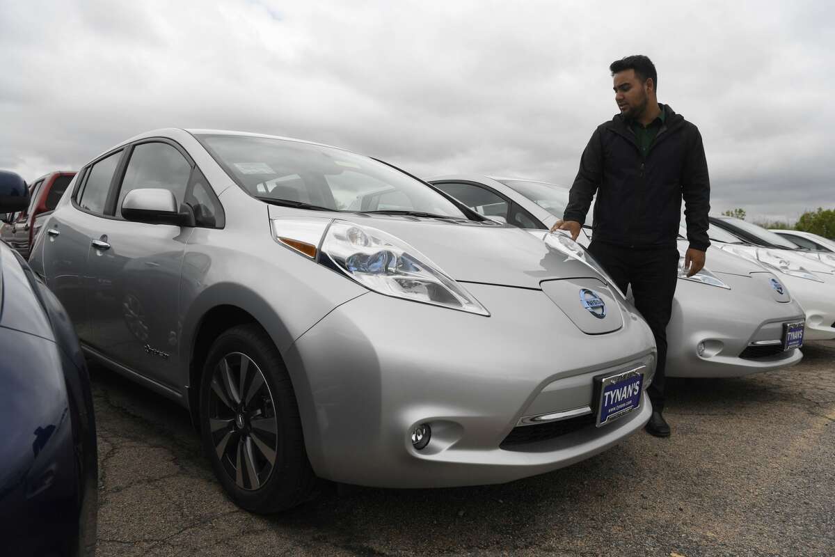 Sales associate Miguel Lopez stands next to all electric Nissan Leaf cars for sale at Tynan's Nissan May 17, 2016. (Photo by Andy Cross/The Denver Post via Getty Images)