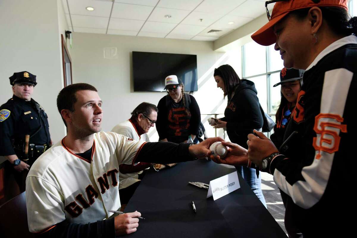 Catcher Buster Posey autographs a baseball for Annette De Jesus of Dublin as the San Francisco Giants hold their FanFest event at AT&T Park in San Francisco, CA, on Saturday February 11, 2017.