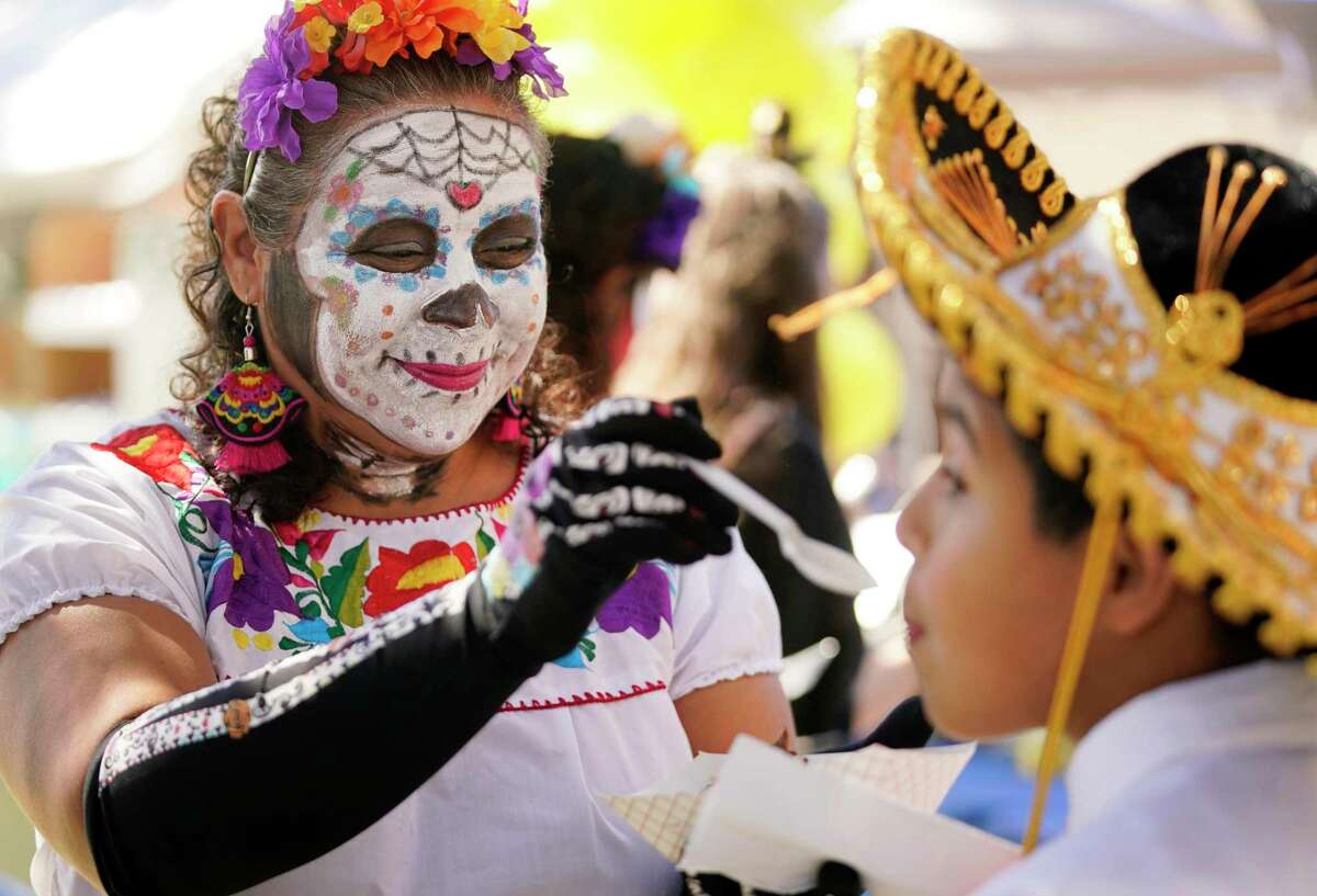 Brenda Anaya gives her son, Isaac Anaya, 12, a bite from her mole chicken taco during the MECA Dia de los Muertos Festival Oct. 30, 2021 in Houston.