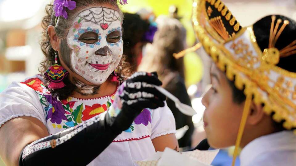 Brenda Anaya gives her son, Isaac Anaya, 12, a bite from her mole chicken taco during the MECA Dia de los Muertos Festival, 1900 Kane St., Saturday, Oct. 30, 2021 in Houston.