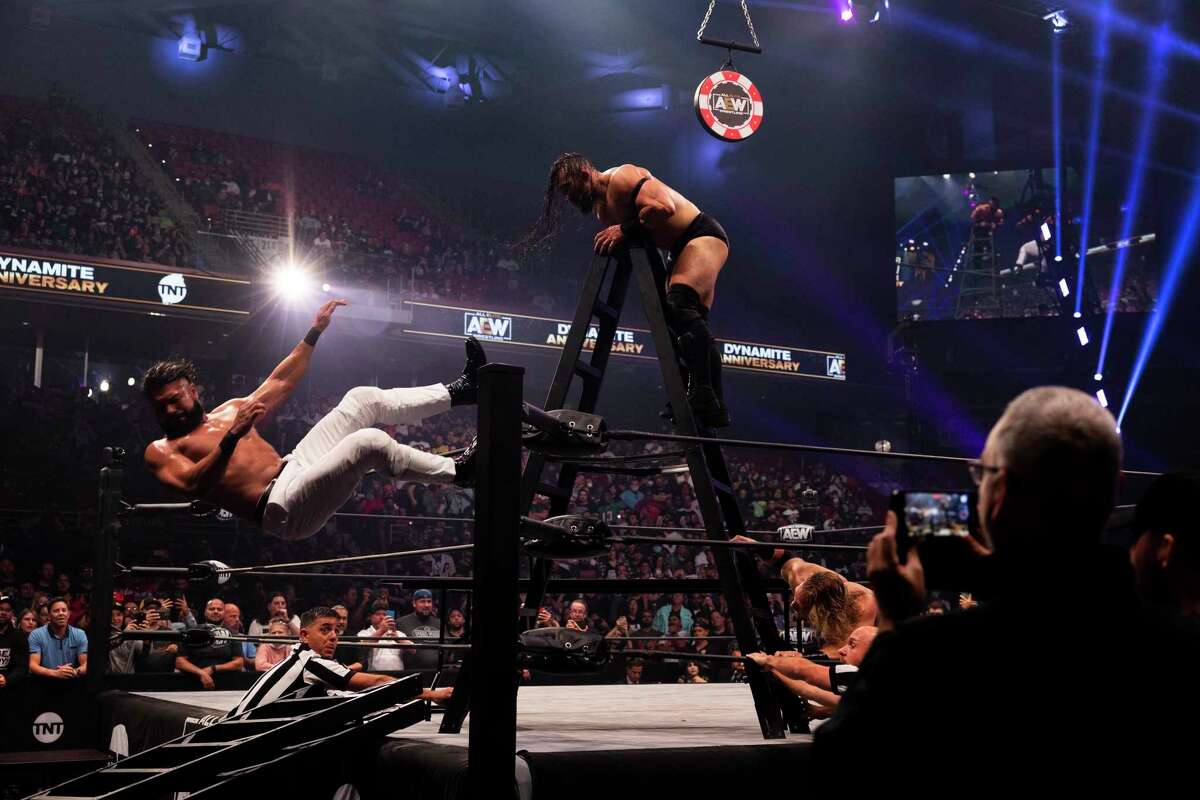 Pac (center) throws Andrade El Idolo from the ladder in the Casino Ladder Match at the AEW Dynamite show in Philadelphia.