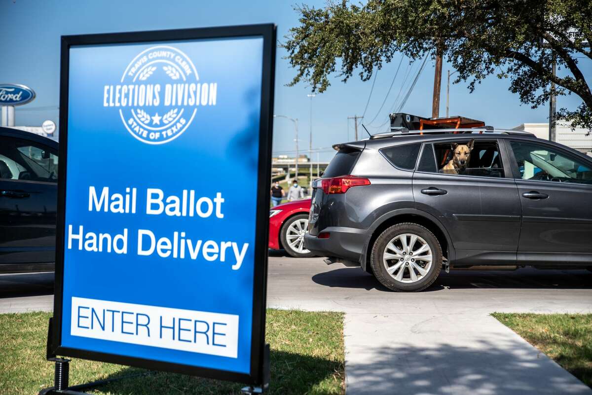 AUSTIN, TX - OCTOBER 13: A dog looks out the car of a voter while they approach a mail in ballot drop off location on October 13, 2020 in Austin, Texas.