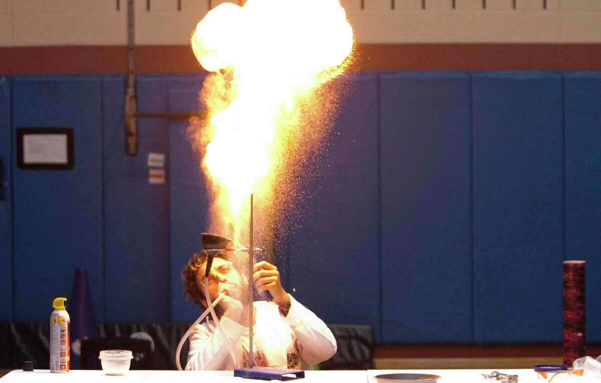 Brian Pagani lights a combustable powder into a fireball during his Mad Science "Fire & Ice" Show for second graders at Cos Cob School in Greenwich, Conn., on Friday November 5, 2021. The Science Enrichment Committee planned the interactive science show, bringing back Brian's show for a second time. The students were in awe as they witnessing dragon breath, a fire cannon, combustion, dry ice geysers and other cool science experiments.
