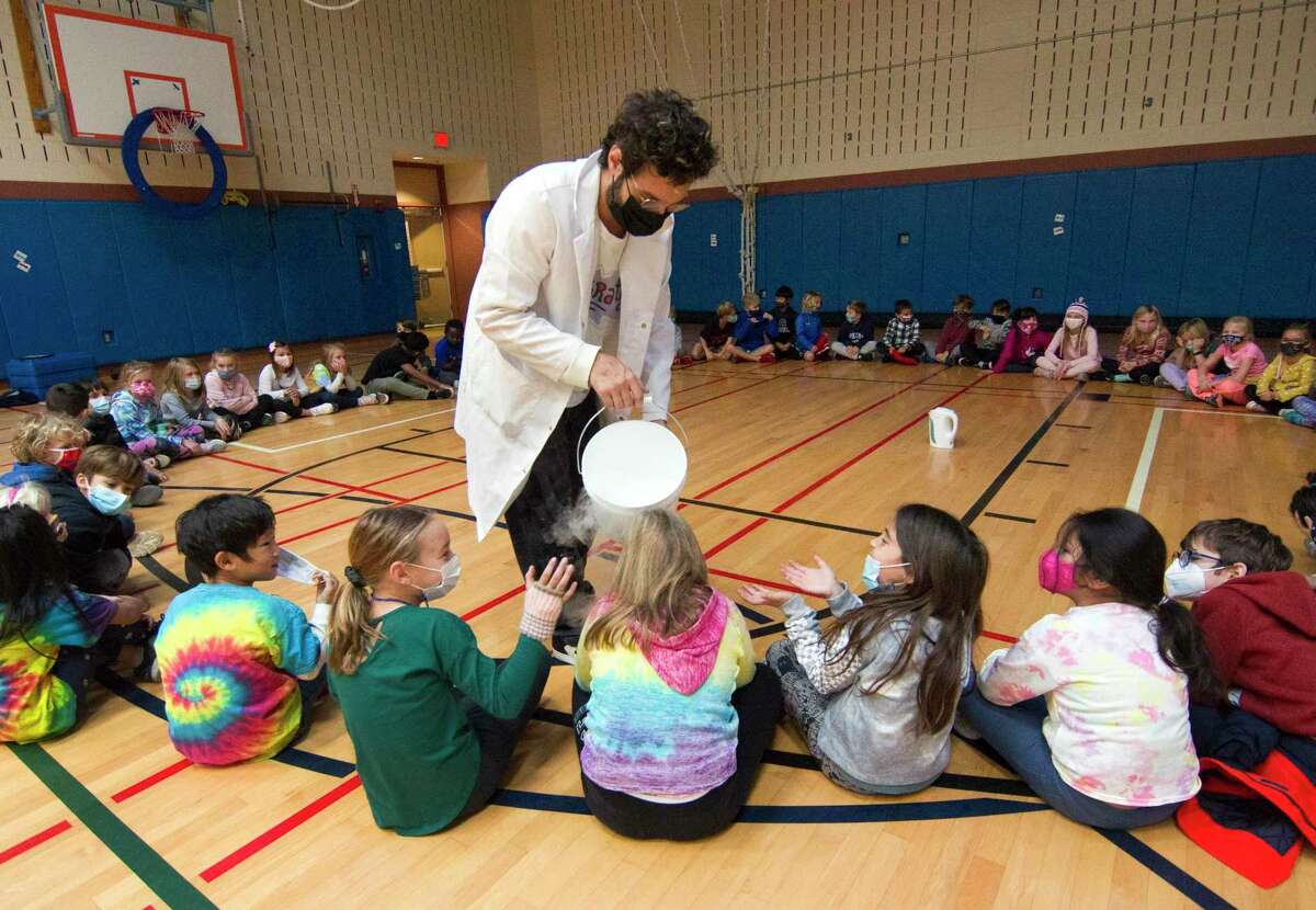 Brian Pagani gives kids a dry ice shower during his Mad Science "Fire & Ice" Show for second graders at Cos Cob School in Greenwich, Conn., on Friday November 5, 2021. The Science Enrichment Committee planned the interactive science show, bringing back Brian's show for a second time. The students were in awe as they witnessing dragon breath, a fire cannon, combustion, dry ice geysers and other cool science experiments.