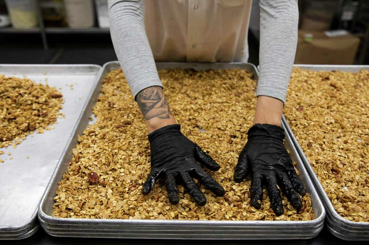 Daniela Tejeda spreads out mixed oats on a baking sheet before putting them in the oven at Nana Joe's Granola production facility in San Francisco, Calif. Wednesday, November 3, 2021. Nana Joe's Granola is seeing price rises and supply shortages because of the supply chain crisis and global warming affecting agricultural crops.