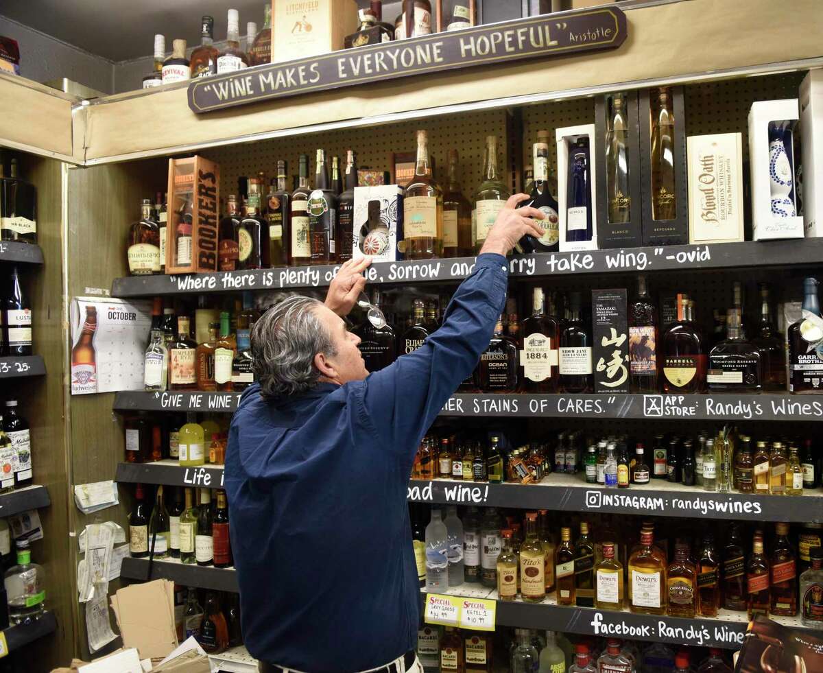 Randy Caravella, owner of Post Wines & Spirits, organizes the tequila shelf at his store in the Cos Cob section of Greenwich, Conn. Thursday, Oct. 28, 2021. Randy's Wines has experienced shortages in tequila and champagne due to supply chain issues, which are affecting many other local businesses as well.