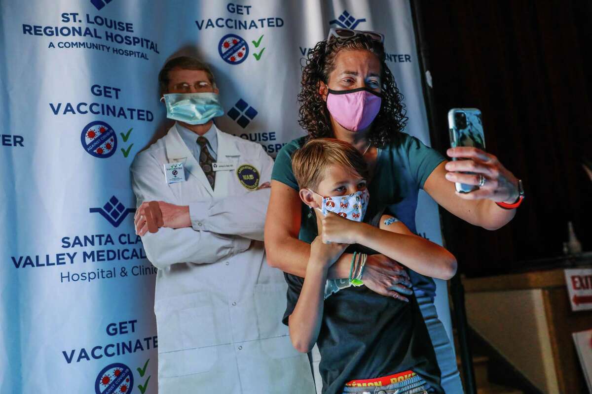 Mom Kate Elsley takes a selfie with her son Finn Washburn, 9, as they pose with a cutout of Dr. Anthony Fauci after her kids got the COVID-19 vaccine at Emmanuel Baptist Church in San Jose.