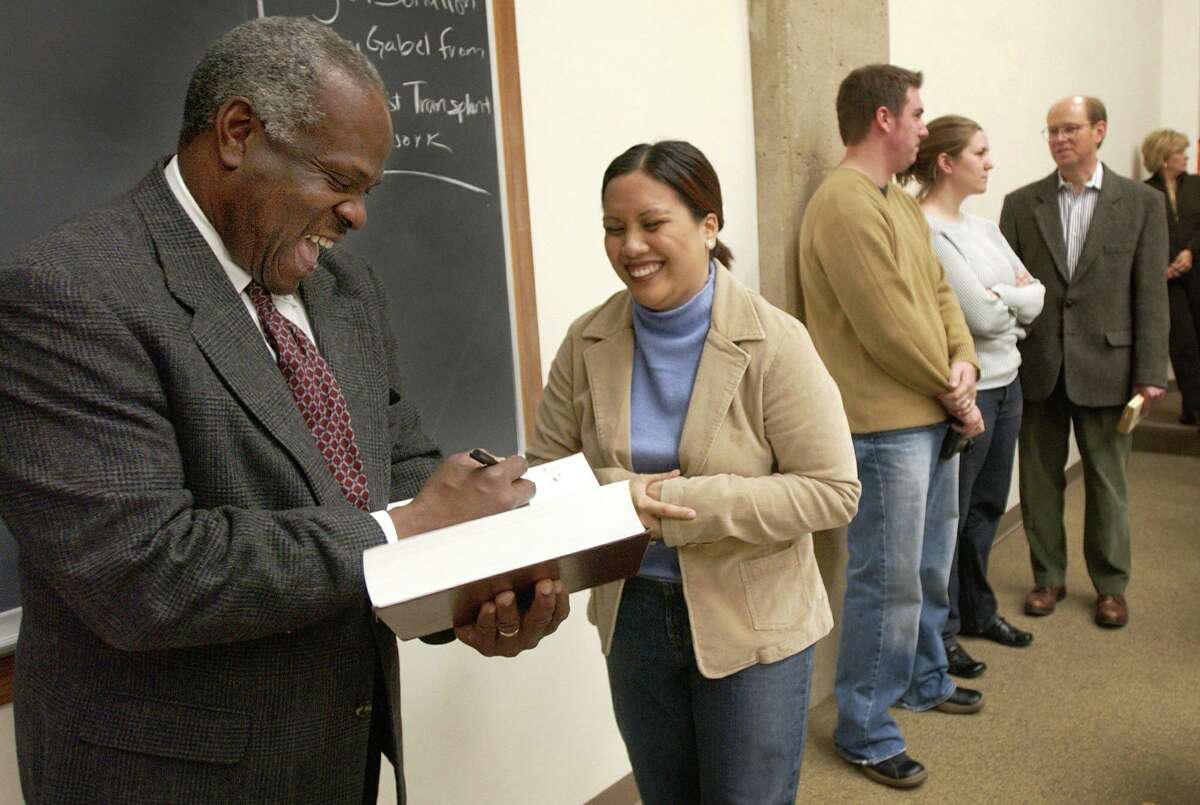 Supreme Court Justice Clarence Thomas, left, autographs a text book, Oct. 28, 2002, for first-year law student Angela Agustin during a visit with faculty, students and alumni at Kansas University School of Law in Lawrence.