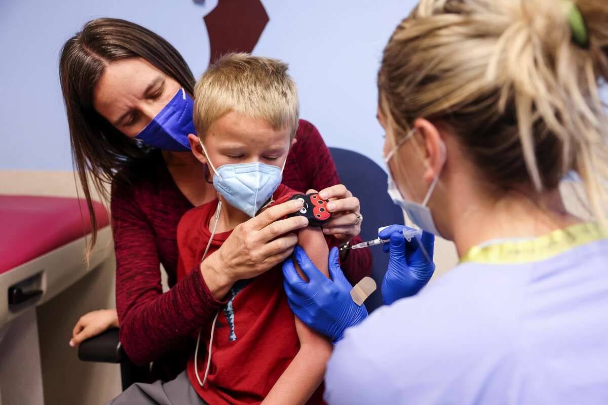 Jill Holm-Denoma, left, comforts her son, Tyler Holm-Denoma, 5, as National Jewish Health registered nurse Emily Cole, right, administers a pediatric COVID-19 vaccine on Wednesday, Nov. 3, 2021 in Denver, Colorado. 