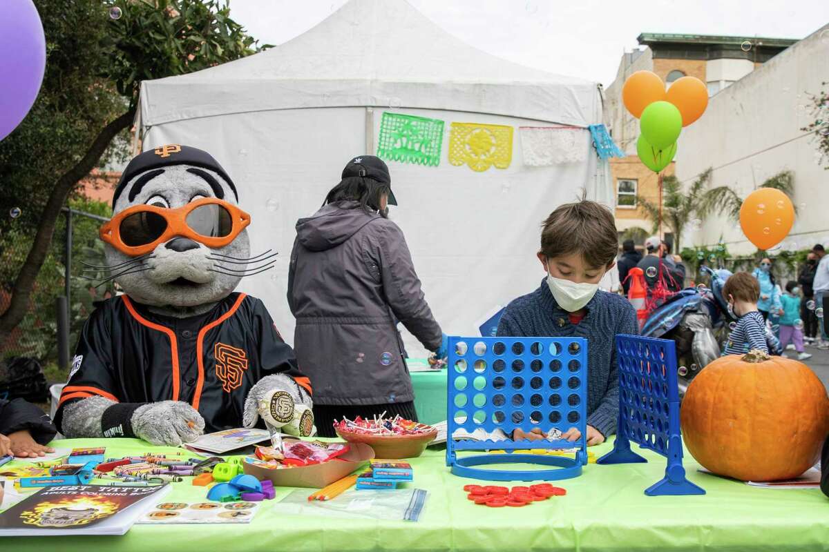 Liam Ravizza, 8, plays with Lou Seal after receiving his shot at the neighborhood vaccination site in San Francisco’s Excelsior neighborhood Saturday.