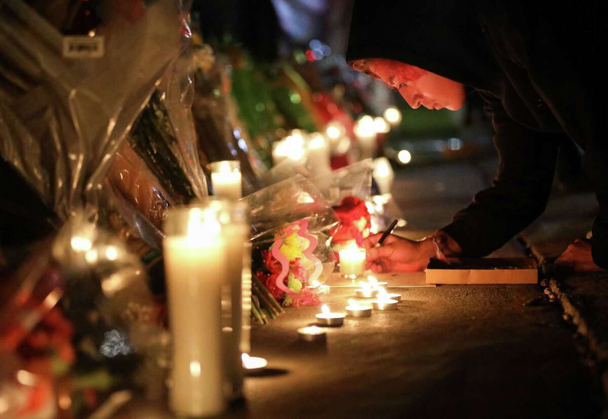 A person signs a card at a memorial for those who died at the Astroworld music festival the night before, on Saturday, Nov. 6, 2021, at NRG Park in Houston.