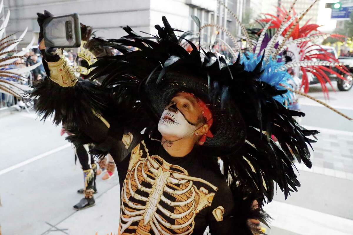 A parade participant makes selfies during the first citywide Dia de los Muertos Festival and Parade at Sam Houston Park Saturday, Nov. 6, 2021 in Houston, TX.