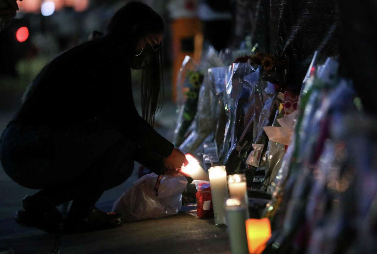 A woman lights a candle at a memorial for those who died at the Astroworld music festival the night before, on Saturday, Nov. 6, 2021, at NRG Park in Houston.