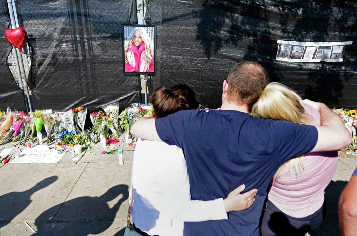 A group of people hug after placing a large framed photo of victim Madison Dubiski on the fence among the Astroworld Festival memorial items along Westridge St. at Kirby Dr. in NRG Park Sunday, Nov. 7, 2021 in Houston. They said they are cousins but they did not want to be identified. Eight were killed and multiple people were injured as Travis Scott was performing at Saturday’s Astroworld Festival.