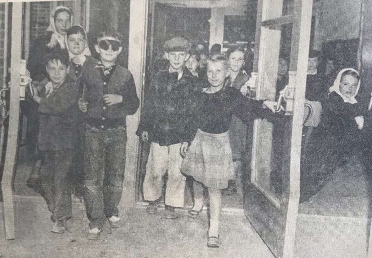Gary Smith, left, and Helen Sweebe, right, hold open the door for their classmates, who include Paula Craig, John Dodge, Janet Horning and Janet Blalock, to leave Eastlawn Elementary School. May 1948