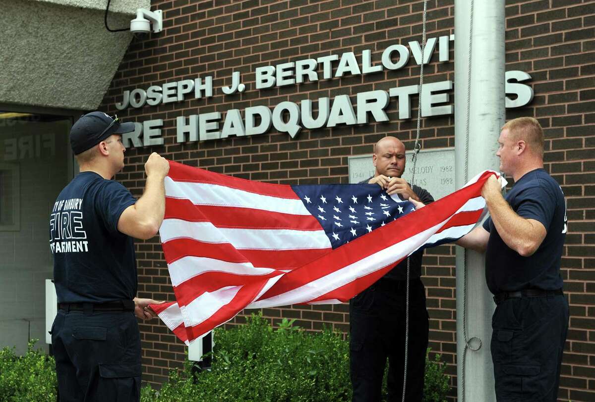 From left, Firefighters Scott Yaglowski, Jason Culbreth and Adam Horosky lower and fold an American flag that flew of the Danbury Fire Department at the New Street headquarters, Tuesday, July 25, 2017. A late Danbury resident donated more than $142,000 to the Danbury Fire Department.