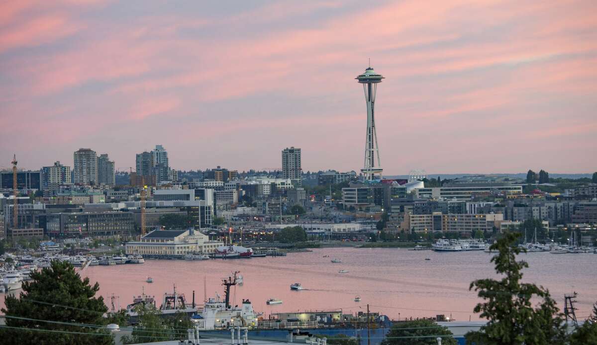 A pink cloudy sunset over a downtown lakefront harbor on Lake Union in Seattle.