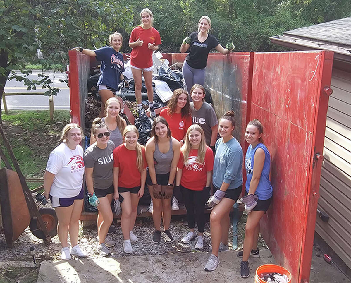 Volunteers from Alpha Xi Delta from SIUE pose in a dumpster after doing a cleanup project with Rebuilding Together Southwest Illinois in the backyard of a senior disabled woman.