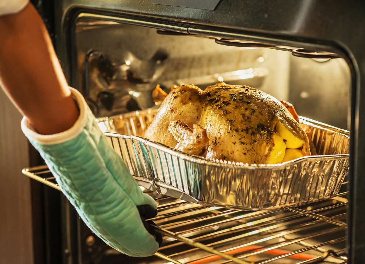 A file image of a person reaching for a turkey in the oven. 