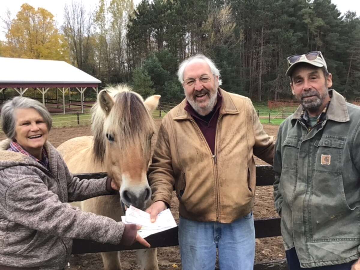 Mary Van Dorp (left), Northern Pathways Equine Center executive director, accepts a donation from Al Frye and Jeff Wagar of Men Who Care Manistee County.