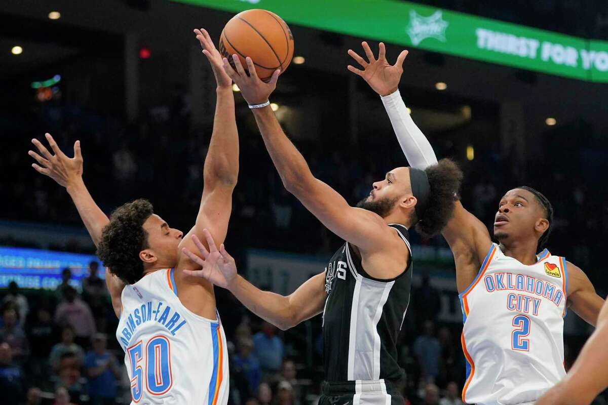 Spurs guard Derrick White, center, shoots between Thunder forward Jeremiah Robinson-Earl (50) and guard Shai Gilgeous-Alexander (2) in the first half of Sunday, Nov. 7, 2021, in Oklahoma City. (