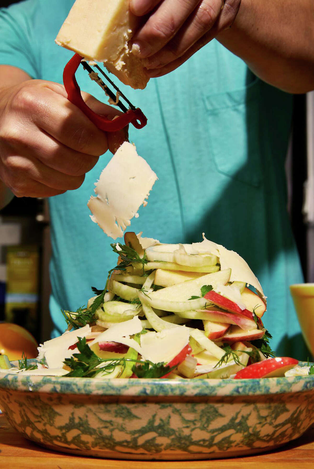 Chef Christian Reynoso shaves white cheddar on a Fennel, Apple and Cheddar Salad.