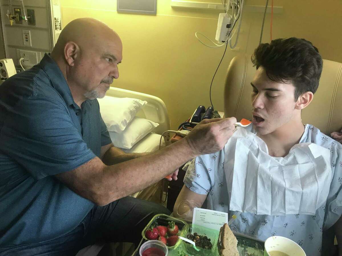 Cal State East Bay guard Julian Lopez is fed by his father, Kenny, after undergoing open heart surgery in September 2018.