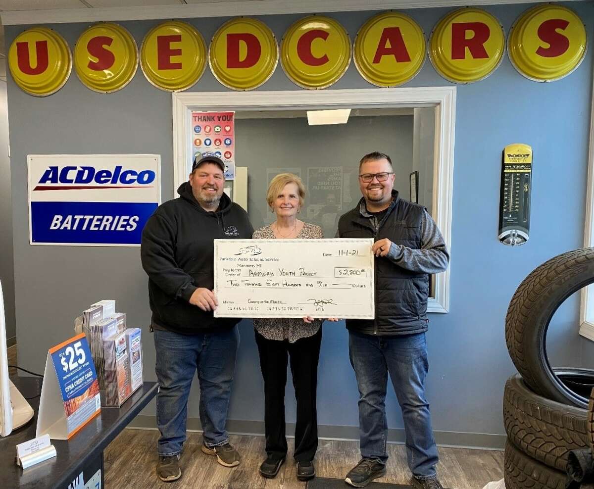 Valarie Bergstrom (center), Armory Youth Project board chair, accepts a donation from John Reed (left) and Tyler Reed of Parkdale Auto Sales & Service.