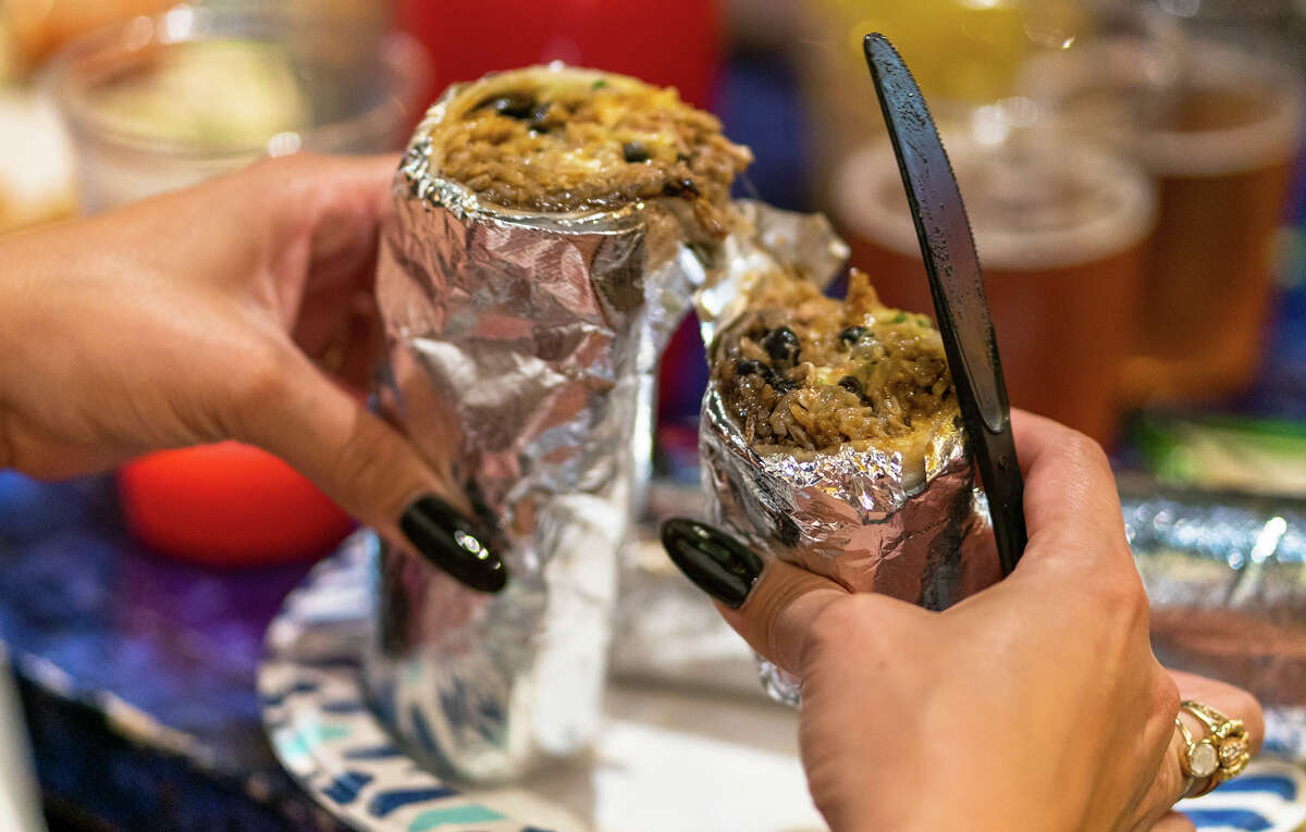 SFGATE's burrito reviewer Cecilia Peña-Govea cuts open the pollo en salsa burrito at El Metate in San Francisco, on Thursday, Nov. 3.