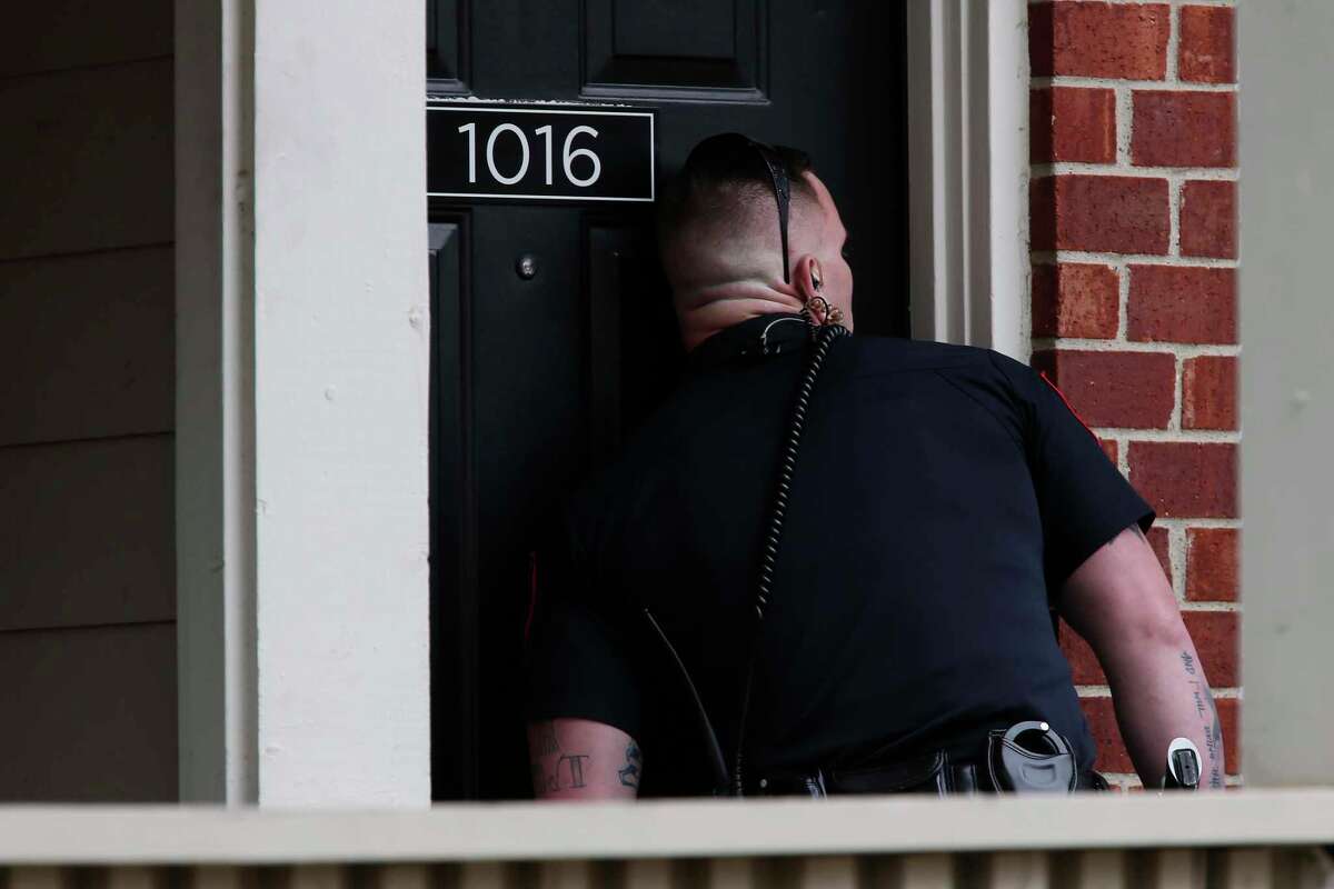 Officer Brandon Thomas of the Bedford Police Department listens for movement inside an apartment where a domestic violence suspect lives. Under the High Point model, in-person visits are meant to add a layer of deterrence.