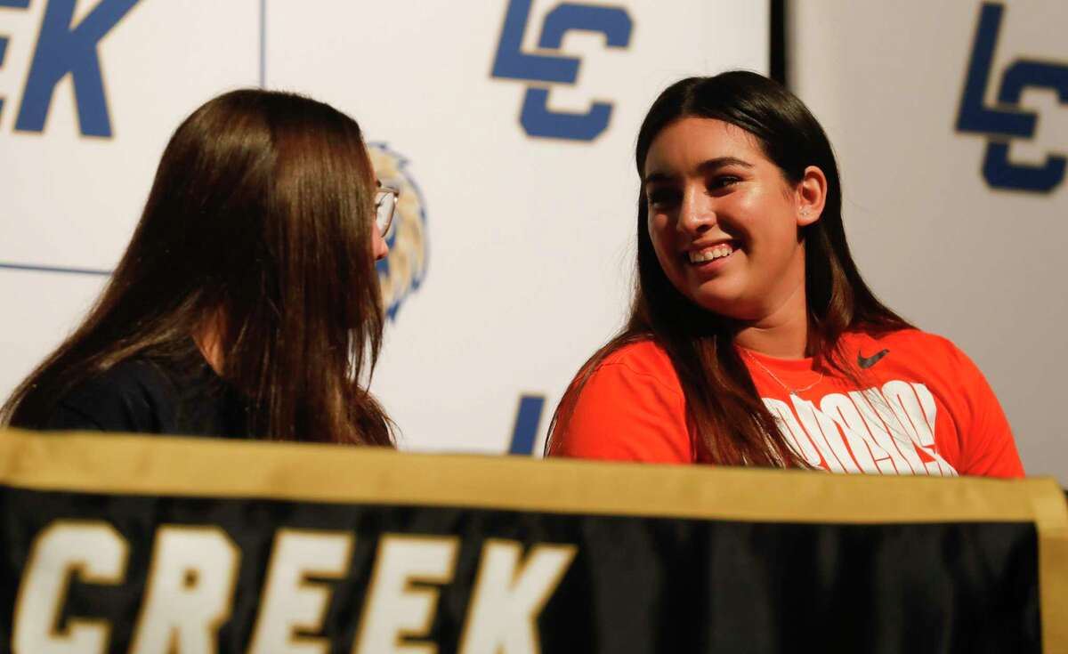 Madelyn Lopez, right, talks with a classmate during a signing ceremony at Lake Creek High School, Wednesday, Nov. 10, 2021, in Montgomery. Lopez signed to play softball for Syracuse, while Rilynn Guynes signed to swim for University of Saint Mary.