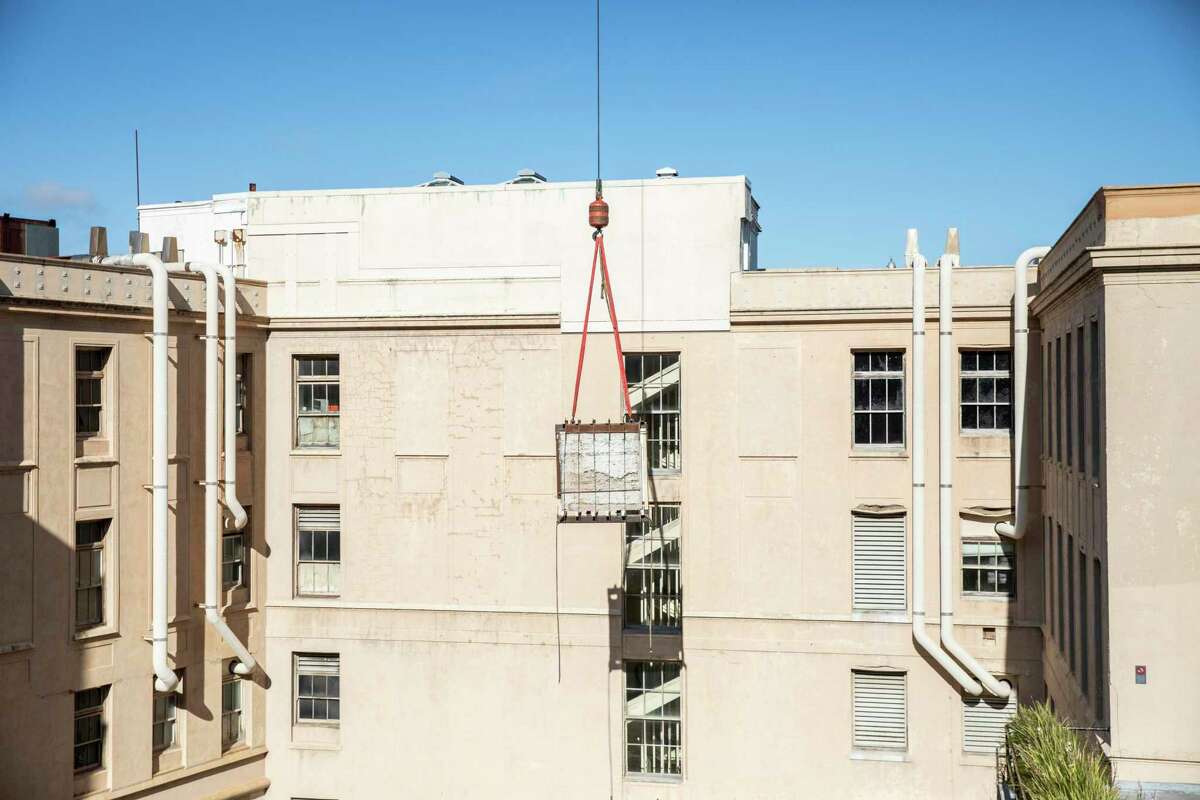 A section of the New Deal-era “History of Medicine in California” mural by by Bernard Zakheim is seen lifted by a crane out of Toland Hall auditorium at UCSF’s Parnassus Heights campus in San Francisco, Calif.