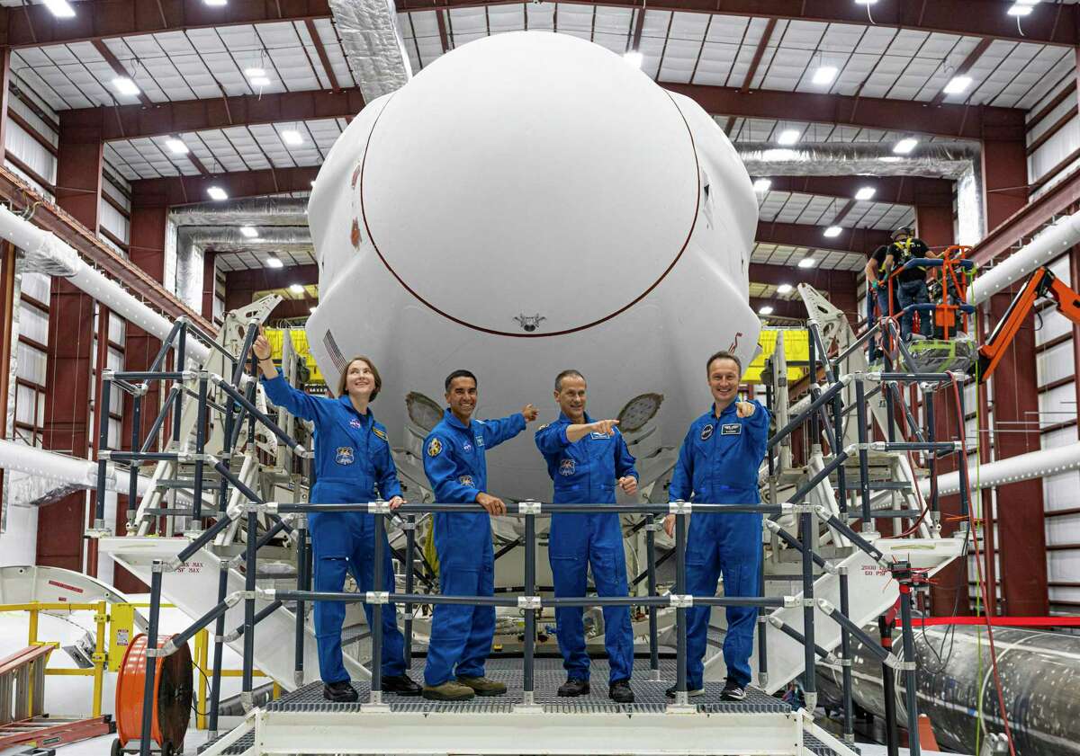 The Crew-3 astronauts stand on the transporter in front of the SpaceX Crew Dragon capsule and Falcon 9 rocket stack inside the SpaceX horizontal processing facility near Launch Complex 39A at NASA’s Kennedy Space Center in Florida on Oct. 26, 2021. From left are NASA astronauts Kayla Barron, Raja Chari and Tom Marshburn, along with Matthias Maurer with the European Space Agency.