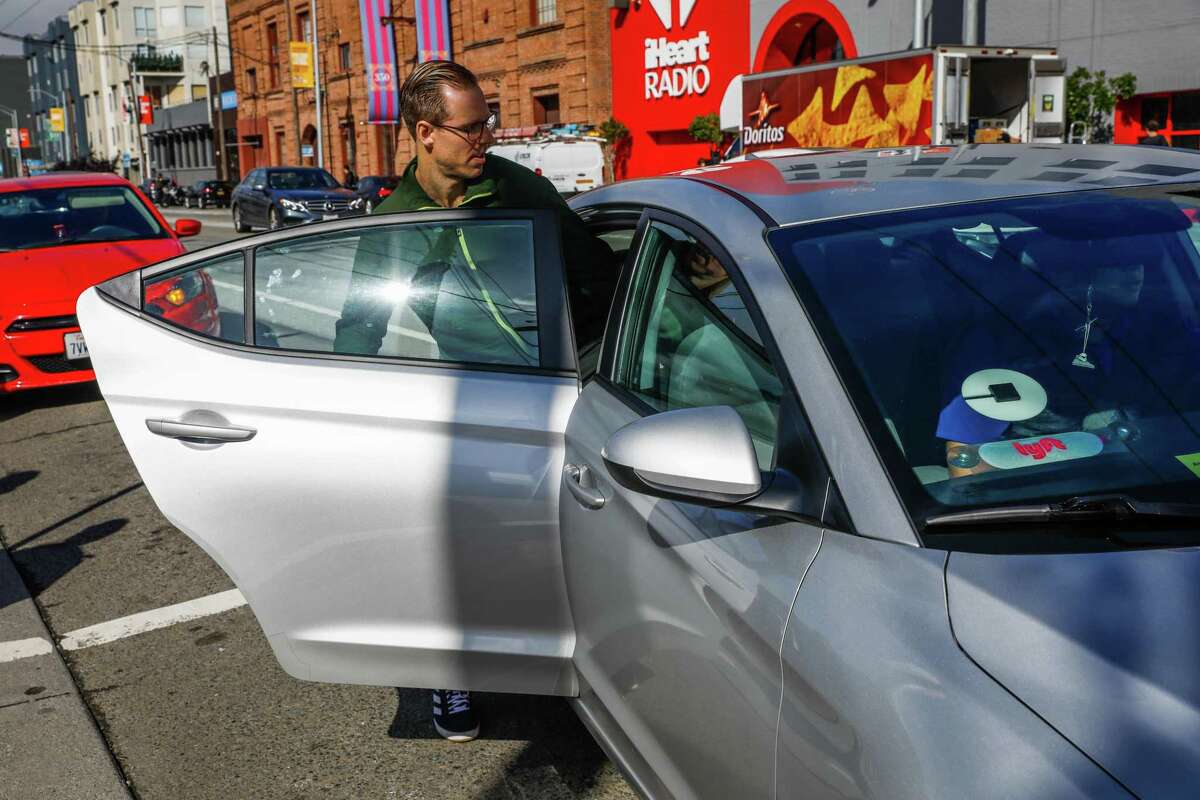 A man gets into a rideshare car outside the Cal Train station on Townsend Street in San Francisco. The U.S. Department of Justice sued Uber on Wednesday for charging “wait time” fees to passengers who need additional time to enter their Uber car because of a disability.