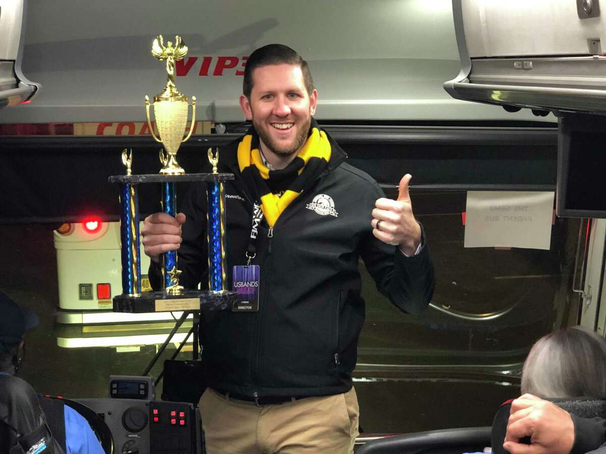 The Trumbull High School Golden Eagle Marching Band director Josh Murphy shows off his trophy.