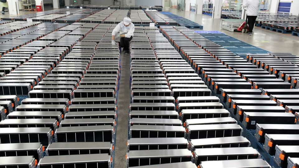 This photo taken on March 12, 2021 shows a worker with car batteries in a factory for Xinwangda Electric Vehicle Battery Co. Ltd in Nanjing, China.