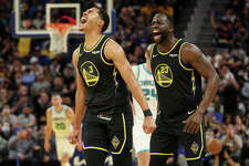 Jordan Poole and Draymond Green of the Golden State Warriors react after Poole made a three-point basket against the Charlotte Hornets on November 03, 2021