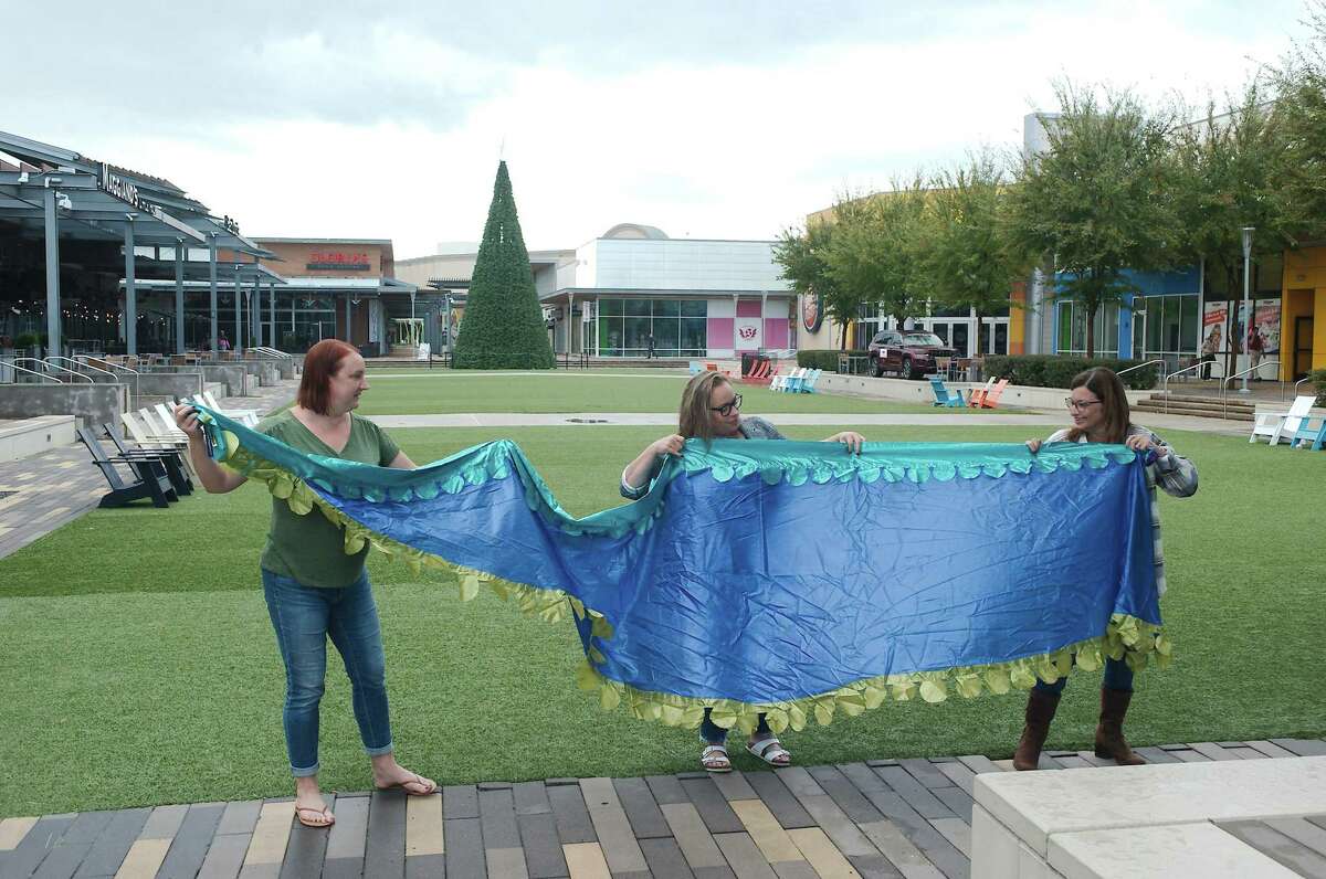 Friendswood Fine Arts volunteers Dawn Saunders,  Sara Peters and Suzanne Banfield examine a banner that will be hung for the group’s Art on the Lawn event scheduled for Nov. 20-21 at Baybrook Mall.