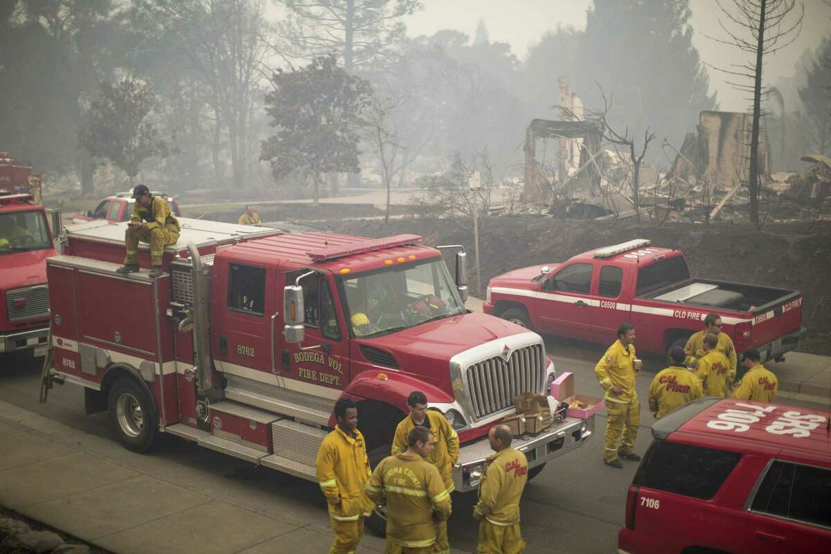 Santa Rosa firefighters gather in a neighborhood of burned houses near Fire Station 5, which was also by fire, in October 2017.