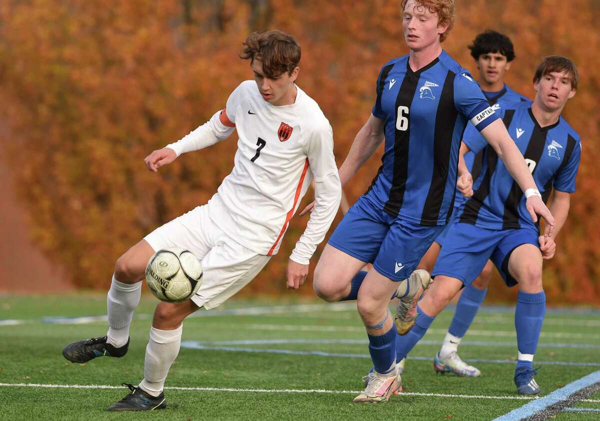 Ridgefield’s Fisher Mills plays the ball while Darien’s James Galvin (6) defends during the second round of the CIAC Class LL boys soccer tournament in Darien on Thursday.