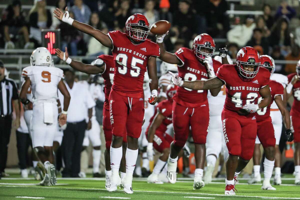North Shore defenders Jacoby Brass (95) and P.J. Douglas (42) celebrate after Kris Ross (97) recovered a Dobie fumble for a turnover during a Class 6A Division I bi-district playoff high school football game Thursday, Nov. 11, 2021 in Houston.