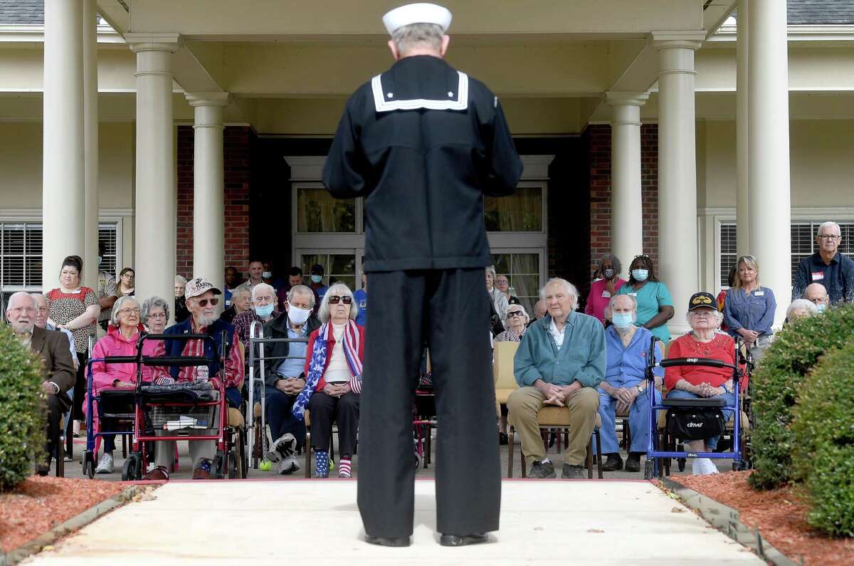 The crowd listens as U.S. Navy veteran Robert Rose speaks about the history of the holiday and its meaning during the annual Veteran's Day ceremony at Calder Woods Thursday. The senior living community is home to veterans who served in several wars, many of whom gathered outside for the traditional salute and words honoring all those who have served. Photo made Thursday, November 11, 2021 Kim Brent/The Enterprise