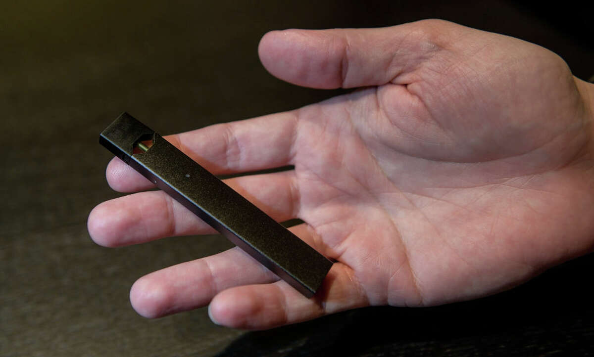 A man holds an e-cigarette of the manufacturer "Juul" in his hand. 