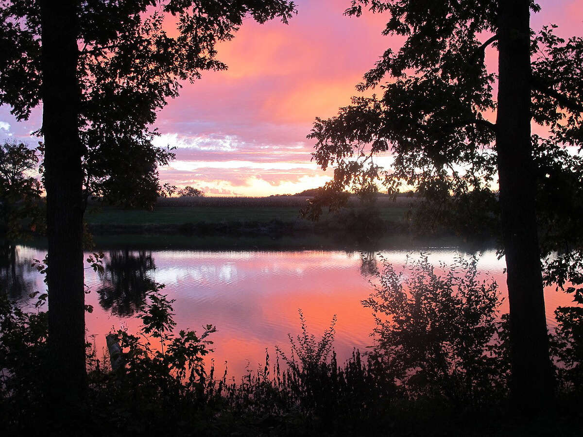Sunrise paints the sky over the Roodhouse reservoir with pastel colors.