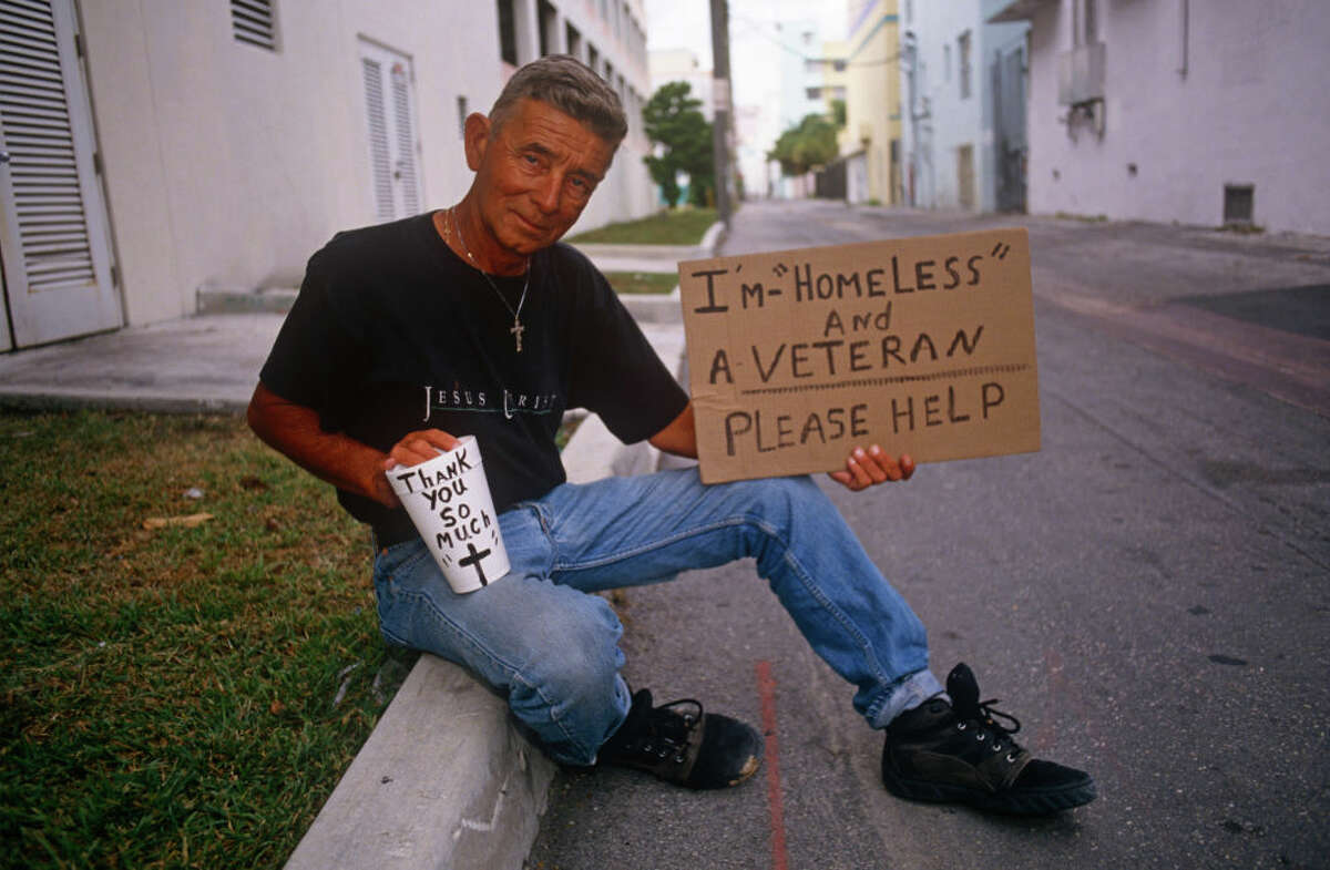 A homeless veteran asks for donations.