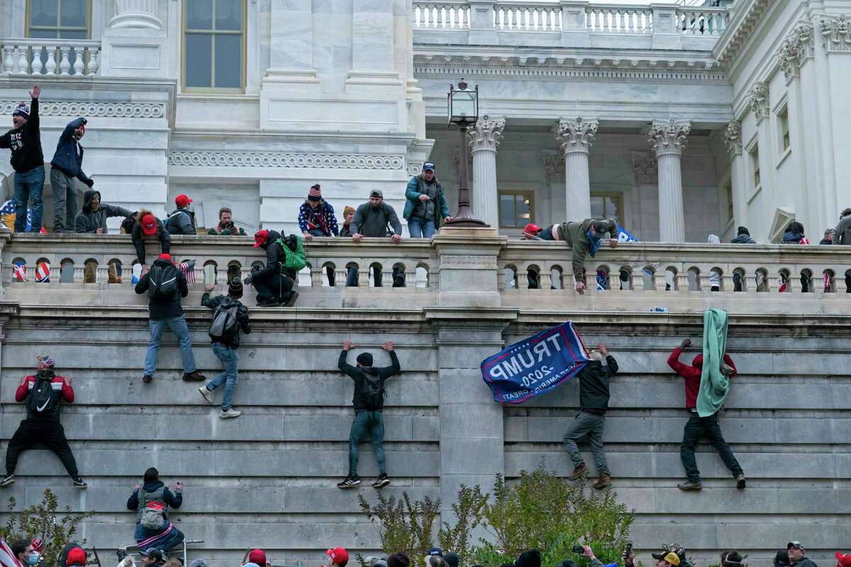 FILE - In this Jan. 6, 2021 file photo, rioters climb the west wall of the the U.S. Capitol in Washington. First, some blamed the deadly Jan. 6 attack on the Capitol on left-wing Antifa antagonists, a theory quickly debunked. Then came comparisons of the rioters as peaceful protesters, or even “tourists." Now, Trump allies rallying in support of those people charged in the Capitol riot are calling them “political prisoners," a stunning effort to revise the narrative of that deadly day. (AP Photo/Jose Luis Magana, File)