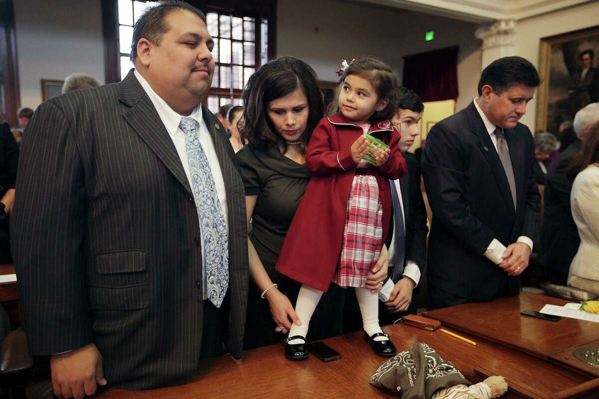 Cinco Guillen, 2, looks over at her father, Rep. Ryan Guillen, D-Rio Grande City, during the invocation at the start of the 83rd Texas Legislature at the State Capitol in Austin, Tuesday, Jan. 8, 2013. With them is his wife, Dalinda, (cq). On the right is Rep. Richard Pena Raymond, (tilde over n in Pena) and his son, Aren, (cq).