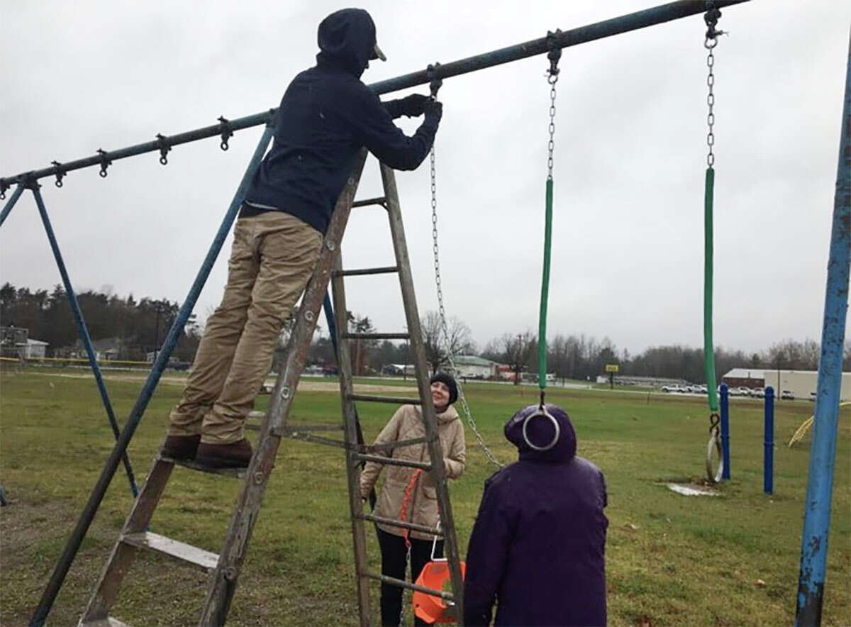 A group of volunteers install new swings at the playground at Morley Community Center. 